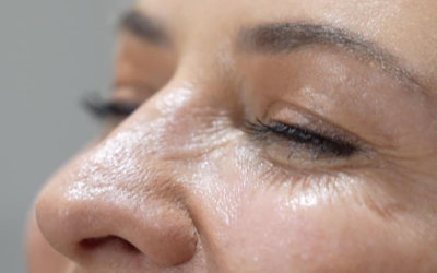 Close-up of a woman's face with a focus on the nose and closed eye, highlighting skin texture and fine wrinkles.