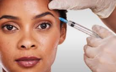 Close-up of a woman's face as a clinician in gloves administers a facial injection near her temple.