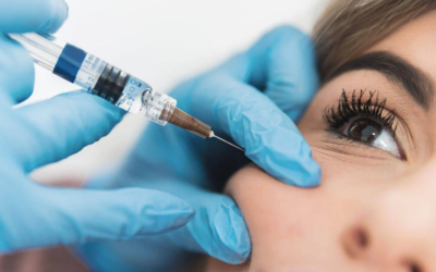 Medical professional wearing blue gloves injects a syringe near a patient's eye.