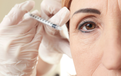 Medical professional wearing blue gloves injects a syringe near a patient's eye.