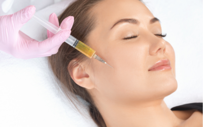 Woman with closed eyes receives a cosmetic facial injection, administered by a clinician wearing pink gloves.