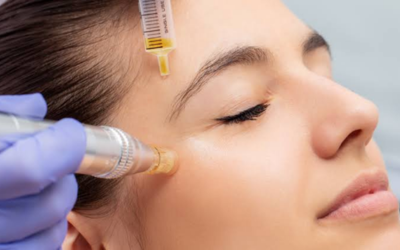 Close-up of a woman with eyes closed receiving a facial injectable; a clinician in purple gloves holds a syringe near her cheek.