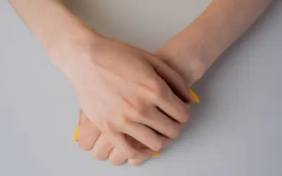 Two hands clasping a small yellow object on a gray surface.